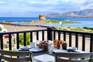 a table with plates of food on a balcony with the ocean at Residence Hotel La Pelosetta in Stintino
