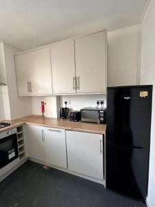 a kitchen with white cabinets and a black refrigerator at City Nights - London in London