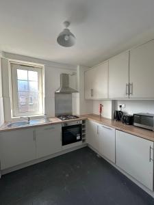 an empty kitchen with white cabinets and a window at City Nights - London in London
