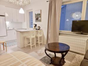 a living room with a table and a kitchen at Studio Porin Oksi, home away home in Pori city center, free parking in Pori