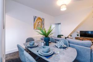 a living room with a table and a blue couch at Sleek and Stylish 3 BR Home Mcr in Manchester