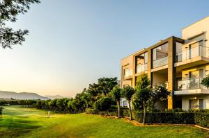 ein Gebäude mit einem grünen Hof davor in der Unterkunft El Plantío Golf Resort in Alicante