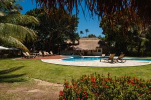 a yard with a swimming pool with chairs and a house at Bangalôs do Gameleiro in Praia dos Carneiros