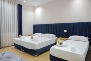 2 łóżka w pokoju z niebieskimi zasłonami w obiekcie Hotel Krial w mieście Berat