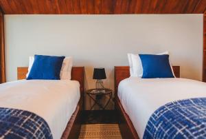 2 camas con almohadas azules en un dormitorio en Cabanas do Pico 1B, en Canto da Areia