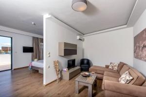 a living room with a couch and a tv at Eurohotel Katrin Suites in Stalida