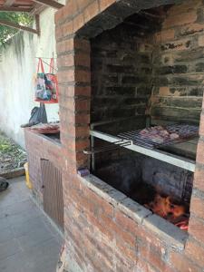 - un four en brique avec de la viande sur un grill dans l'établissement Casa de Férias Arborizada, à Canavieiras