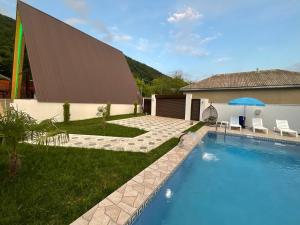 a swimming pool in front of a building with a house at 3Gozel Aframe Villa Gabala in Gabala