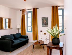 un salon avec un canapé et une plante en pot dans l'établissement Le Jules Appart'Hotel, à Romans-sur-Isère