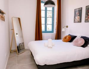 - une chambre avec un lit blanc et une fenêtre dans l'établissement Le Jules Appart'Hotel, à Romans-sur-Isère