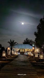 a night view of a building with a moon in the sky at Berber Camp in Merzouga