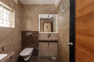 a bathroom with a toilet and a sink and a mirror at Classic Heights Serviced Apartments, near IIM Bangalore, in Bengaluru
