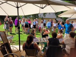a group of people sitting at tables under an umbrella at Village 17 gites, Piscine, Restaurant , 2 gites avec SPA, 3km de Conques in Conques +112 photos