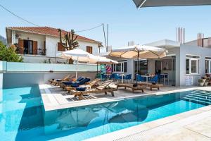 a swimming pool with chairs and umbrellas next to a house at BLUE STAR APARTHOTEL in Nydri