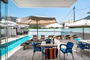 an outdoor patio with tables and chairs and a pool at BLUE STAR APARTHOTEL in Nydri