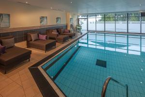 a swimming pool with couches and chairs in a building at Boutique Hotel die Mittagspitze Superior in Damuls