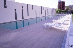 una fila de sillas blancas sentadas junto a una piscina en Hermoso y Moderno Loft en Dunas de Montemar Concòn, en Concón