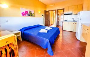 a bedroom with a blue bed and a kitchen at Residence Hotel La Pelosetta in Stintino