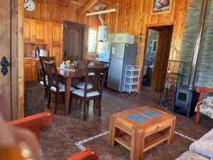 a kitchen and dining room with a table and a refrigerator at Cabaña Ojo del Volcán in Pucón