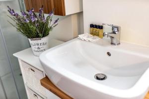 a bathroom sink with a vase of purple flowers on it at FLOATING SEA HOUSE AURORA in Portorož