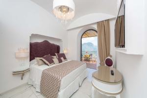 a white bedroom with a bed and a balcony at Villa Amore in Ravello