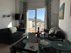 ein Wohnzimmer mit einem Tisch mit einer Flasche Wein in der Unterkunft Nerja Paradise Rentals - Apt Chimenea C2D in Nerja