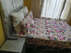 a bed with a floral comforter and pillows at Moonlight Guest House in Benoni