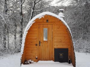 a wooden cabin with a door in the snow at Beniaskie! Lake Lodge in West Masuria in Miłakowo