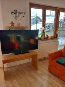 un salon avec une télévision à écran plat sur une table dans l'établissement Haus am Waldrand, à Thiersee