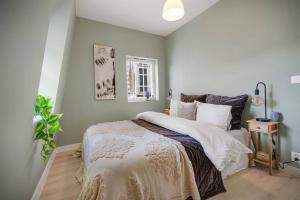 een slaapkamer met een groot bed met witte lakens bij Det grønne huset i Verftsgaten in Bergen