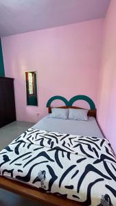 1 dormitorio con 1 cama con edredón blanco y negro en Twentynine Homestay, en Banyuwangi