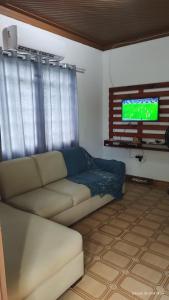 sala de estar con sofá y TV de pantalla plana en Cantinho Caiçara, en Ilhabela