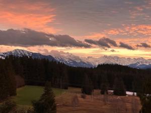 einen Sonnenuntergang über einem Feld mit Bergen im Hintergrund in der Unterkunft Alpentraum: Luxuswohnung mit atemberaubendem Blick in Buchenberg