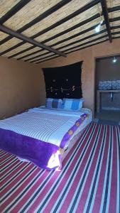 una camera da letto con un grande letto e un pavimento a righe di Mhamid yaya camp & activités a M'Hamid