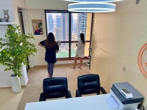 Duas mulheres num escritório a olhar pela janela. em Berloga Capsule JBR em Dubai