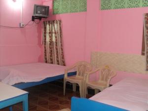 een kamer met 2 bedden en 2 stoelen en een tv bij Hotel UK Nest in Sabari