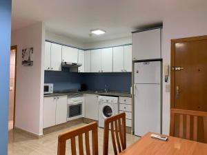 cocina con armarios blancos, mesa y nevera en Experience Valencia Bnb - Rincon del Mar - Apartamento Maravilloso a Canet Playa 100 mt en Canet de Berenguer