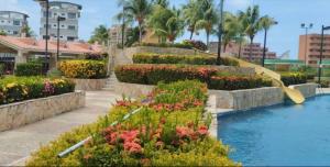 einen Garten mit einem Pool, Blumen und einer Rutsche in der Unterkunft Arriendo Ciudad Flamingo in El Marite