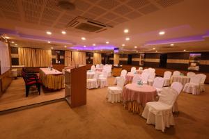 a banquet hall with white tables and chairs and a podium at Hotel PVK Grand Dindigul in Dindigul