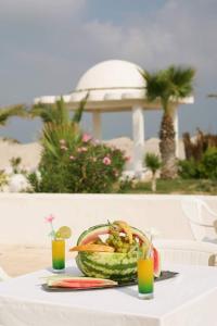 a table with a bowl of watermelon and two drinks at Villa archen in Soliman