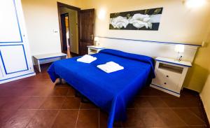 a bedroom with a blue bed with two towels on it at Residence Hotel La Pelosetta in Stintino