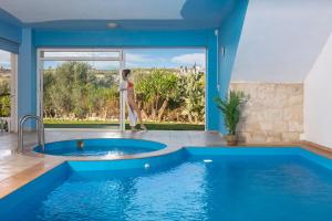 una mujer está parada frente a una piscina en WhiteBlue Spa Villa, By IdealStay Experience, en Heraclión