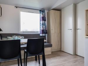 a room with a table and chairs and a window at Compact 4 person chalet in Friesland in De Veenhoop
