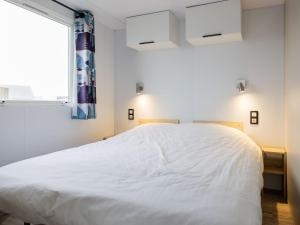 a bedroom with a white bed and a window at Compact 4 person chalet in Friesland in De Veenhoop