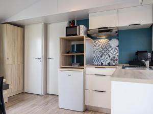 a kitchen with white cabinets and a microwave at Compact 4 person chalet in Friesland in De Veenhoop