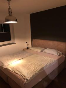 Un dormitorio con una cama blanca con luz. en Stilvolles Apartment - mit E-Auto Lademöglichkeit en Attendorn