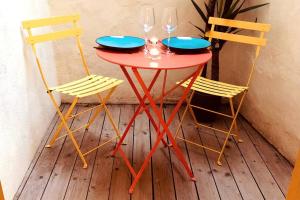 a red table with two chairs and two wine glasses at Cachet Cosy in Nîmes