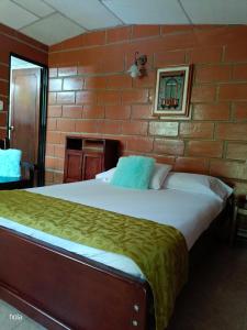 1 dormitorio con 1 cama grande en una pared de ladrillo en Cabañas La Honda, en Guatapé