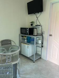 a room with a tv and a table with a microwave at Pada Guesthouse Khaoyai in Mu Si