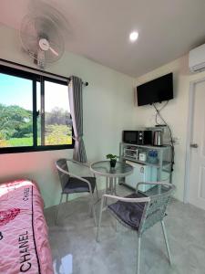Habitación con mesa, sillas y TV. en Pada Guesthouse Khaoyai, en Mu Si